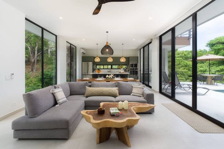 Living room with sectional sofa, open to the dining table, kitchen and pool terrace